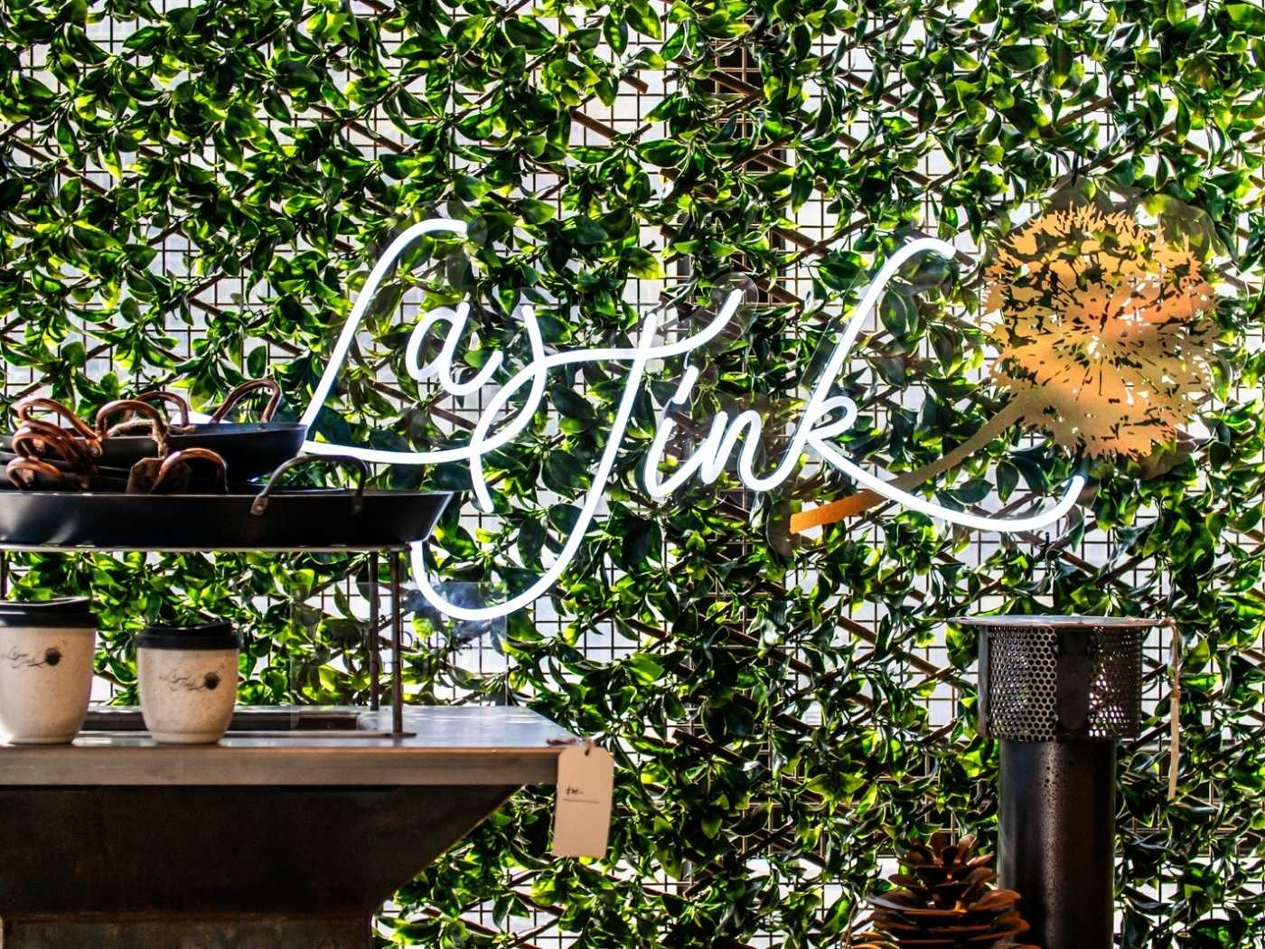 Neon sign with 'LaTink' on a green leafy background