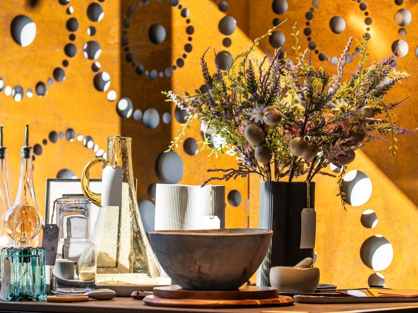 LaTink showroom decorative setting with flowers, vases, and bowls against a geometric-patterned Corten steel garden screen.